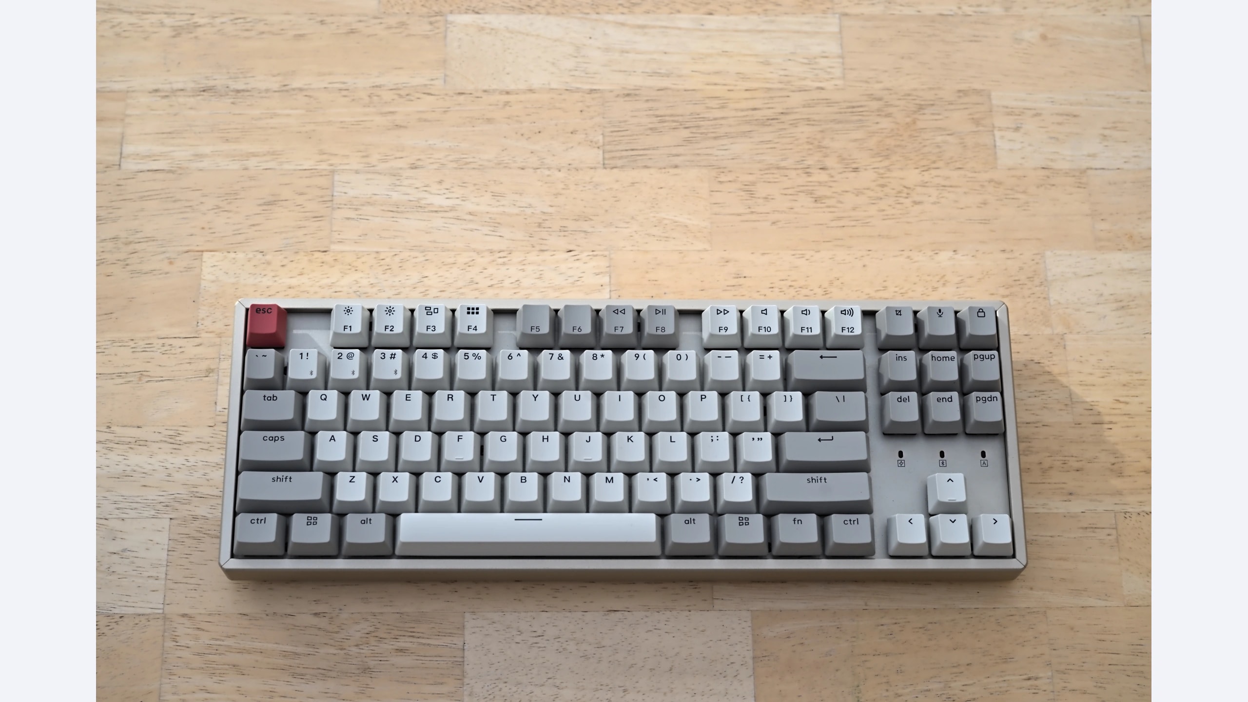 Non-backlit Keychron K8 tenkeyless keyboard with gray keycaps on a wooden desk