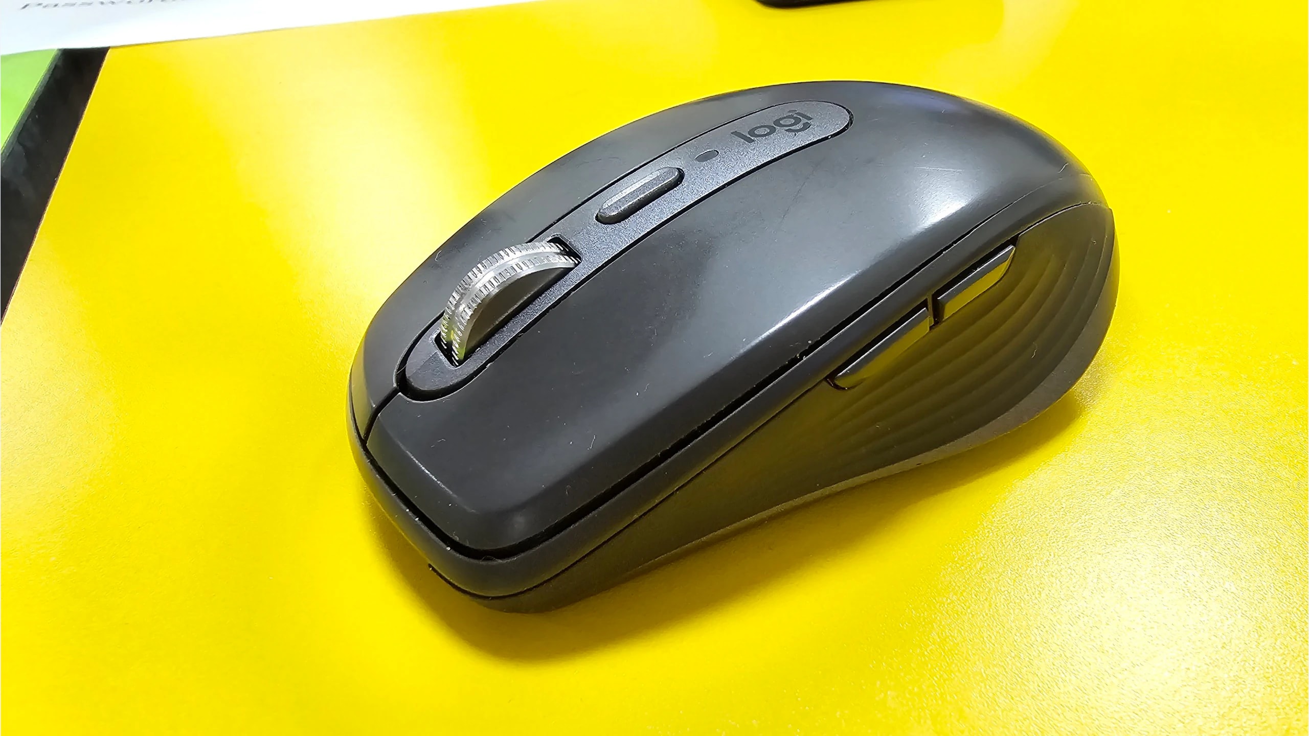 Graphite Logitech MX Anywhere 3 compact mouse on a yellow surface