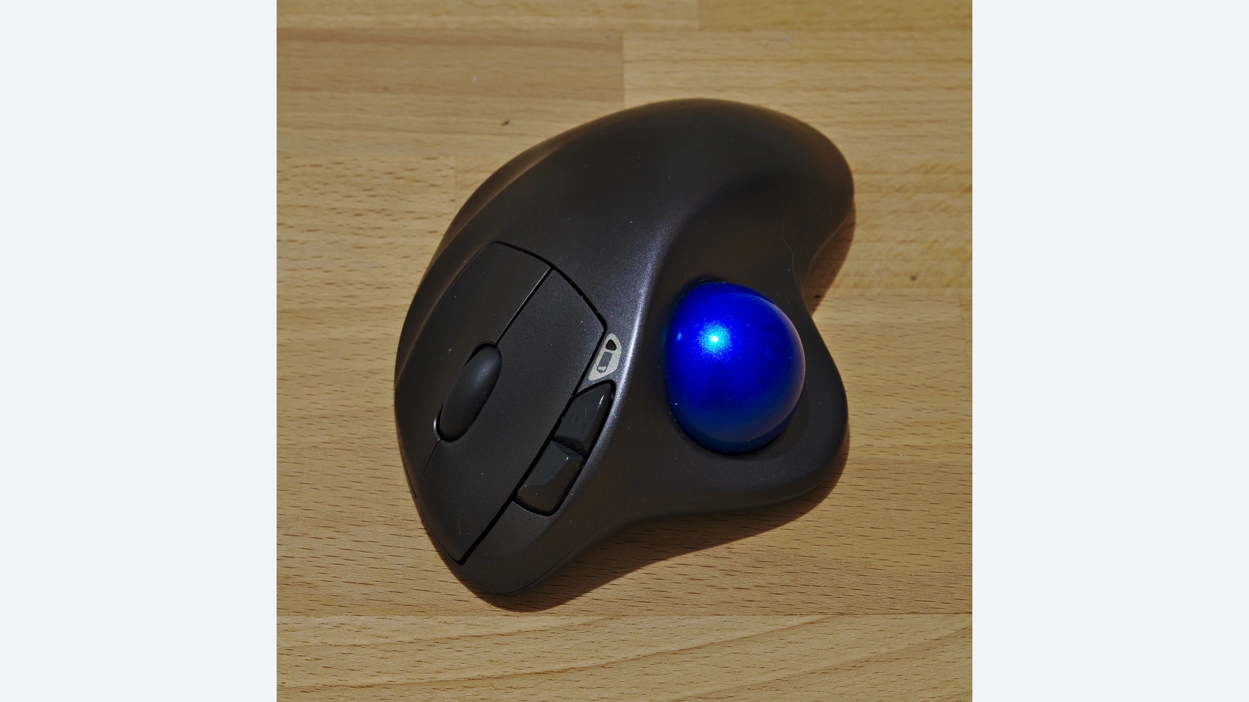 Used Logitech M570 trackball with blue thumb ball on a wooden desk